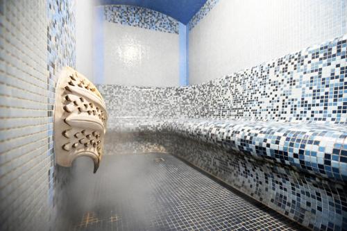 a bathroom with blue and white tiled walls and a sink at Hotel Eger & Park in Eger