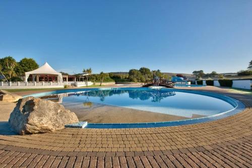 a large swimming pool with a rock in the middle at The Warren Holiday Park - Family Chalet in Abersoch