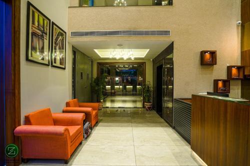 a lobby of a hotel with orange chairs and a bar at The Zenith - A boutique hotel by Hot Millions in Mohali