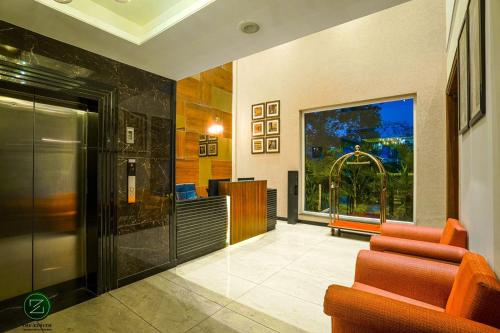 um átrio com cadeiras laranja e uma grande janela em The Zenith - A boutique hotel by Hot Millions em Mohali