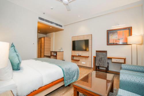 a bedroom with a bed and a tv and a couch at The Zenith - A boutique hotel by Hot Millions in Mohali