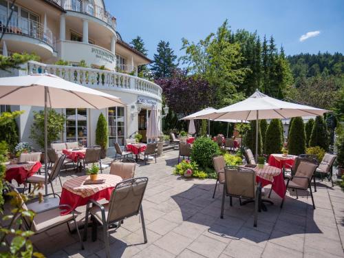 eine Außenterrasse mit Tischen, Stühlen und Sonnenschirmen in der Unterkunft Parkhotel Bad Faulenbach in Füssen