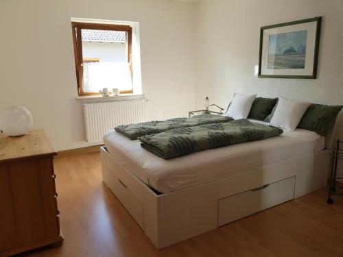 - une chambre avec un grand lit blanc et une fenêtre dans l'établissement Ferienwohnungen Kumpf, à Bad Aibling