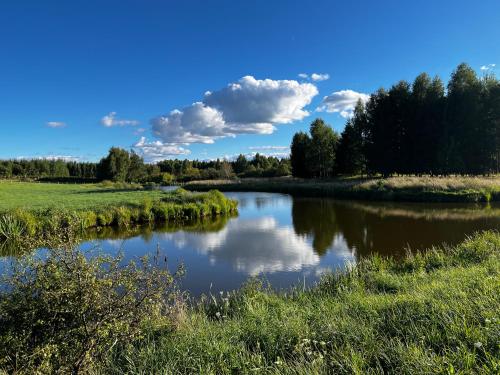 a river in a field with clouds in the sky at Highland Warmia - Gospodarstwo agroturystyczne in Jeziorany