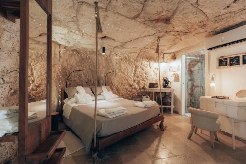 a bedroom with a bed and a stone wall at Grotta Carlotta in Ostuni