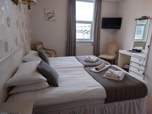a bedroom with a large bed with two towels on it at The Cumberland Hotel in Eastbourne