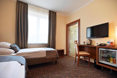 a hotel room with a bed and a desk and a television at Hotel Eger & Park in Eger