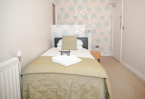 a bedroom with a bed with a yellow blanket at The Cumberland Hotel in Eastbourne