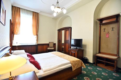 a bedroom with a bed and a television in it at Hotel Eger & Park in Eger
