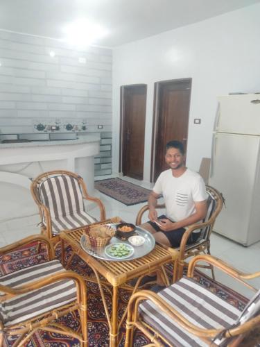 a man sitting in a room with a table and chairs at Jamaica Guest House in Aswan