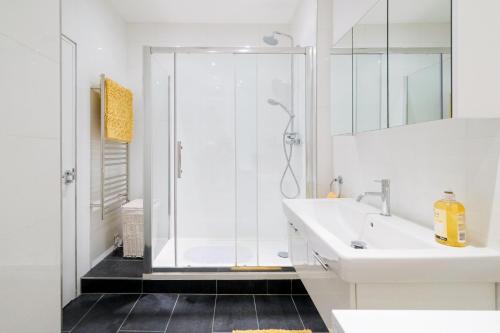 baño blanco con ducha y lavamanos en Lovely 2 bed flat in canal side gated development, en Londres