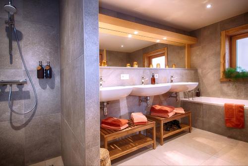 un bagno con due lavandini, una doccia e una vasca di La Ferme des Fingères a Cordon