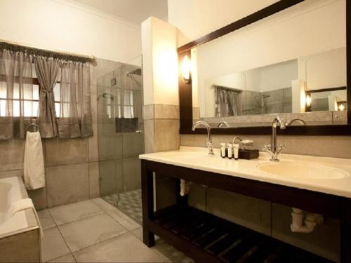 a bathroom with a sink and a mirror and a shower at Kronenhoff Guesthouse in Kirkwood