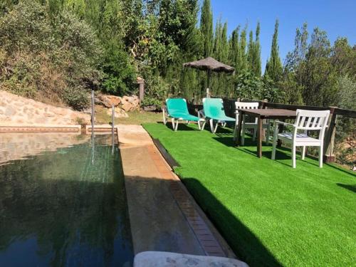 a garden with a table and chairs next to a pool at Apartamento El Mirador Rocabella in El Chorro