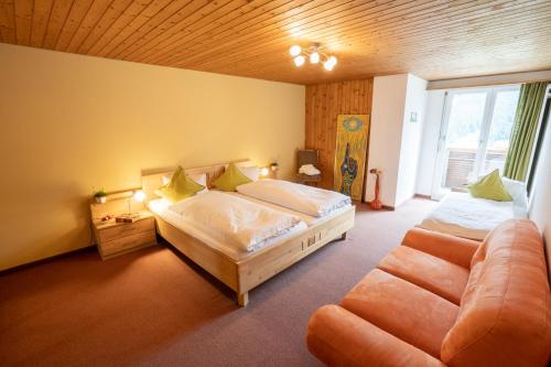a bedroom with two beds and a couch at Hotel Sonne in Wildhaus