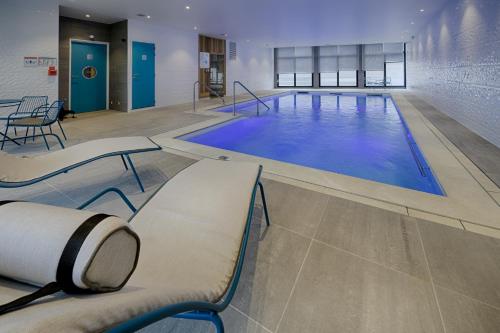 une grande piscine avec de l'eau bleue dans un immeuble dans l'établissement DOMITYS Le Piano Résidence Sénior, à Lille