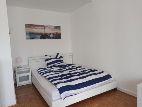 a white bed with a blue and white striped blanket at Central Studio 139 in Düsseldorf