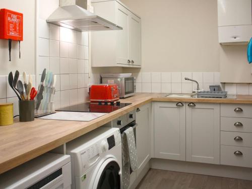 a kitchen with white cabinets and a washer and dryer at Ring Of Bells Cottage - Ukc4274 in Orby
