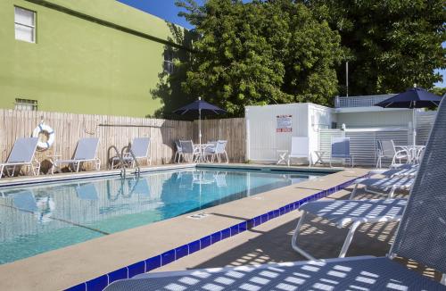 a swimming pool with chairs and umbrellas next to a fence at Southwinds Motel in Key West
