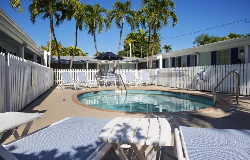 a swimming pool with chairs and a fence and palm trees at Southwinds Motel in Key West