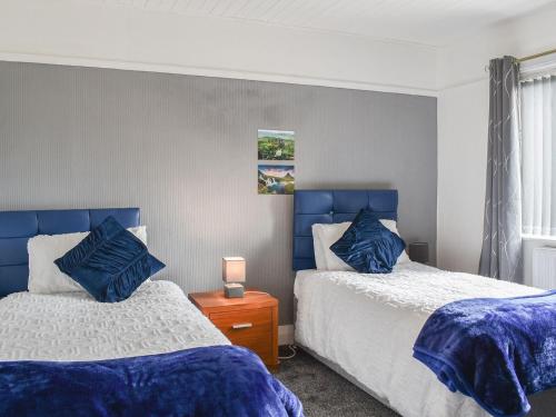 two beds in a bedroom with blue headboards at Huddersfield House, Wood View in Huddersfield