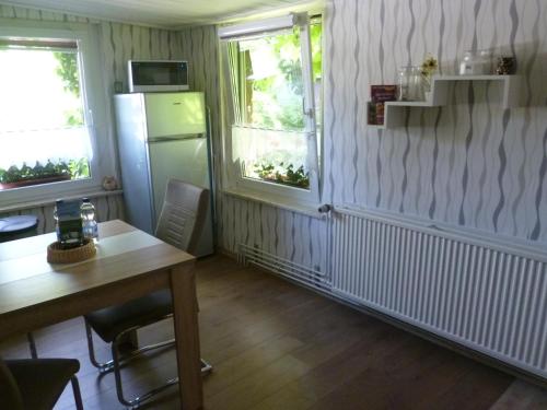 eine Küche mit einem Tisch und einem Kühlschrank sowie 2 Fenster in der Unterkunft Ferienhaus ANNE in Thale