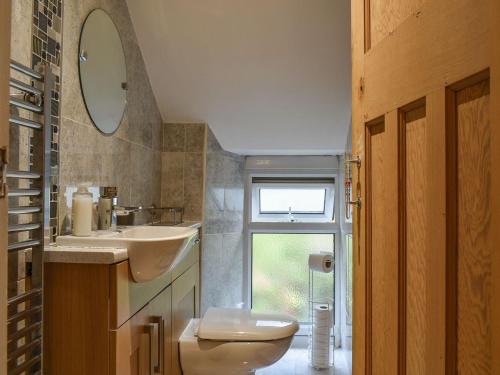 uma casa de banho com um lavatório, um WC e um espelho. em Yew Tree Cottage em Old Brampton