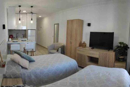 Zimmer mit 2 Betten, einem TV und einer Küche in der Unterkunft Cozy Studio Harbour View in Puerto de la Cruz in Puerto de la Cruz