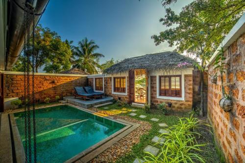 a home with a swimming pool and a house at Coconut Lagoon Kumarakom- CGH Earth in Kumarakom
