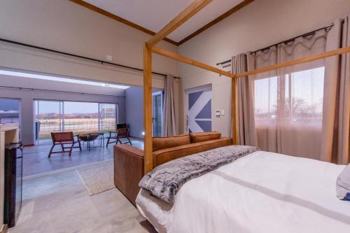 a bedroom with a canopy bed and a dining room at Ugab Game Farm & Lodge in Vingerklip