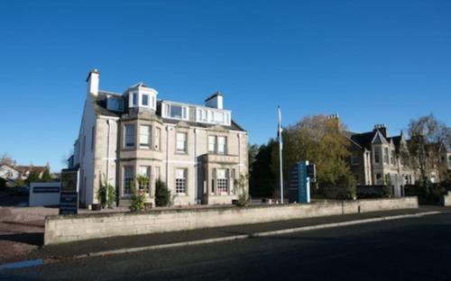 a large white house on the side of a street at Club House Hotel & Restaurant in Nairn