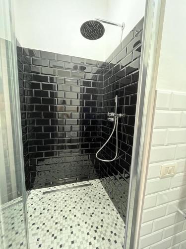 a bathroom with a shower with a black brick wall at 2 Passi Da in Rome