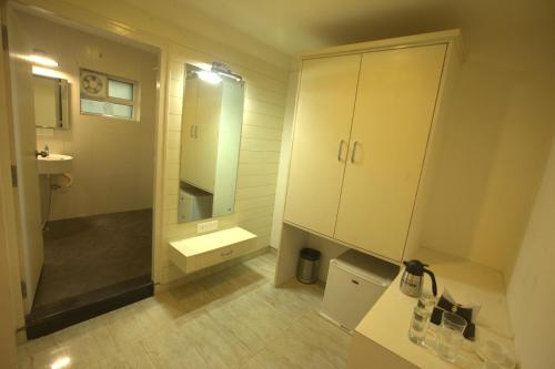 a white bathroom with a sink and a mirror at Royal shades kodihali in Bangalore
