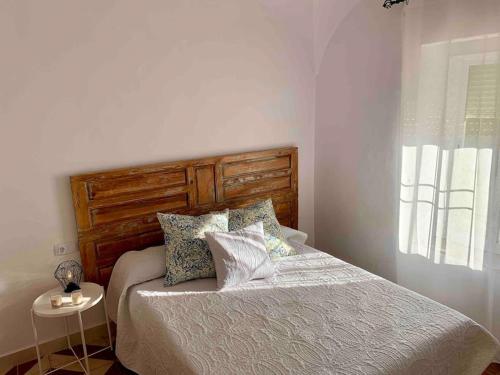 1 dormitorio con cama con cabecero de madera y almohadas en La Casa Rural de María Jesús, 