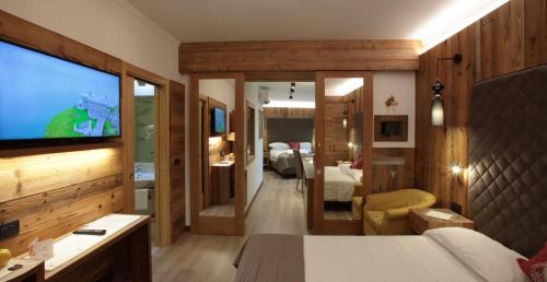a bedroom with a bed and a television in a room at Alexander Hotel Alpine Wellness Dolomites in Molveno