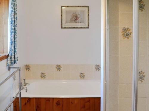 a bathroom with a bath tub with a picture on the wall at Lower Brae in Achnahanat