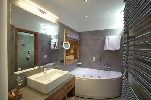 ein Badezimmer mit einer Badewanne, einem Waschbecken und einer Badewanne in der Unterkunft Alexander Hotel Alpine Wellness Dolomites in Molveno