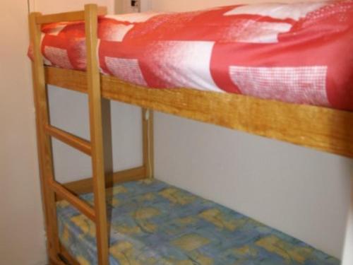 a bunk bed with a red comforter on top of it at Charmant 2 pièces cabine, balcon, 4 pers, proche pistes et commerces aux Adrets - FR-1-557-106 in Les Adrets