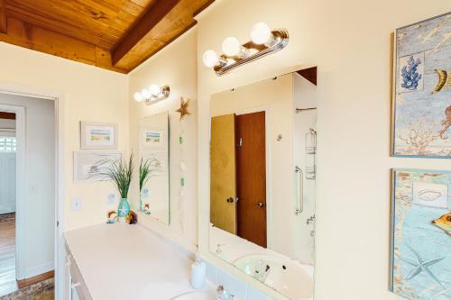 a bathroom with a tub and a sink and a mirror at Ginny's Coastal Cottage in Oak Island