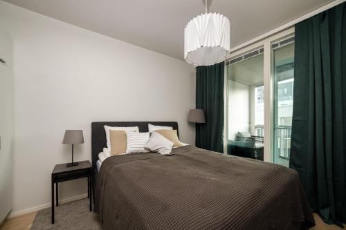 Schlafzimmer mit einem Bett mit grünen Vorhängen und einem Kronleuchter in der Unterkunft ULEABO Neat 48 m2 two-room flat with sauna in Oulu