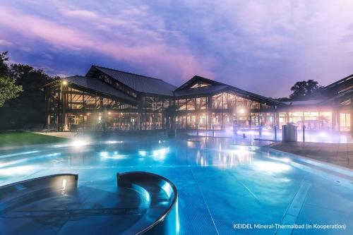 a large building with a swimming pool at night at Dorint Thermenhotel Freiburg in Freiburg im Breisgau