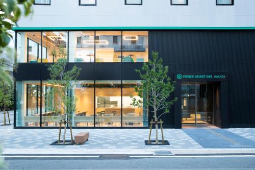 budynek z dwoma drzewami przed nim w obiekcie Prince Smart Inn Hakata w mieście Fukuoka