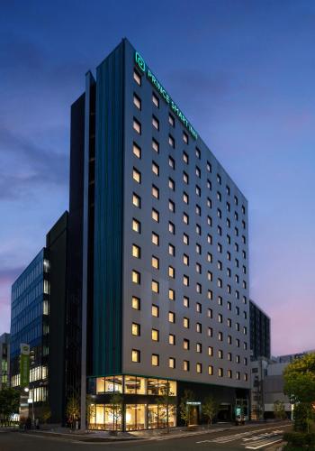 a tall building with a lit up sign on it at Prince Smart Inn Hakata in Fukuoka