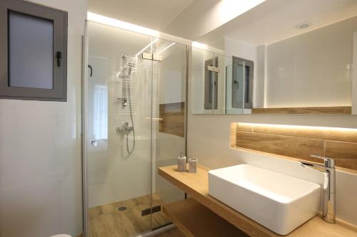 biała łazienka z umywalką i prysznicem w obiekcie IO SUITES w Atenach