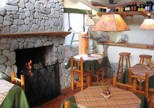 a living room with a stone fireplace and a table at Hostería Traunco in Villa La Angostura