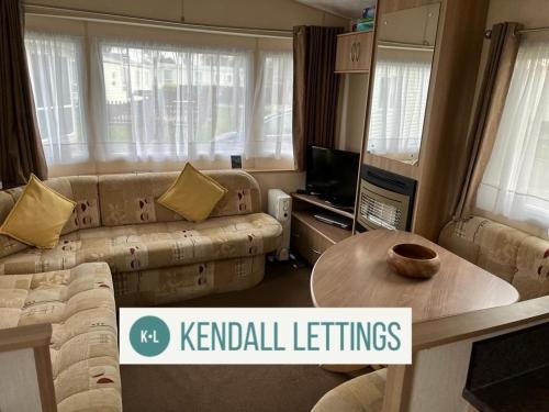 a living room with a couch and a table at Tebay (Green Lawns) in Selsey