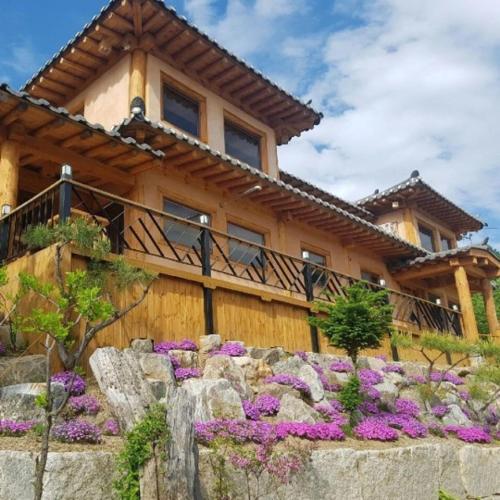 a house with purple flowers in front of it at Saranbang Pension in Gapyeong