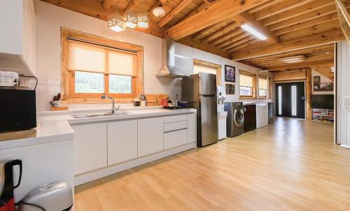 a large kitchen with a sink and a refrigerator at Saranbang Pension in Gapyeong