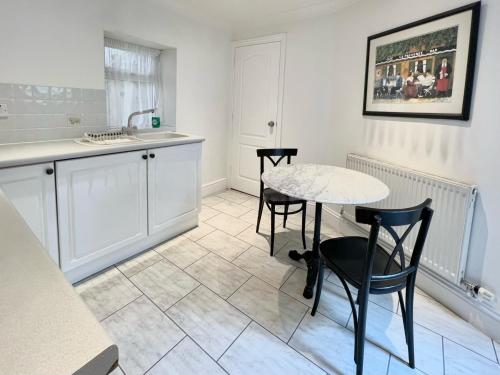 uma cozinha com mesa e cadeiras num quarto em Promenade House em Douglas