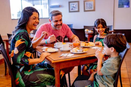 eine Gruppe von Menschen sitzt um einen Tisch herum und isst in der Unterkunft Rio das Pedras Thermas Hotel in Caldas Novas